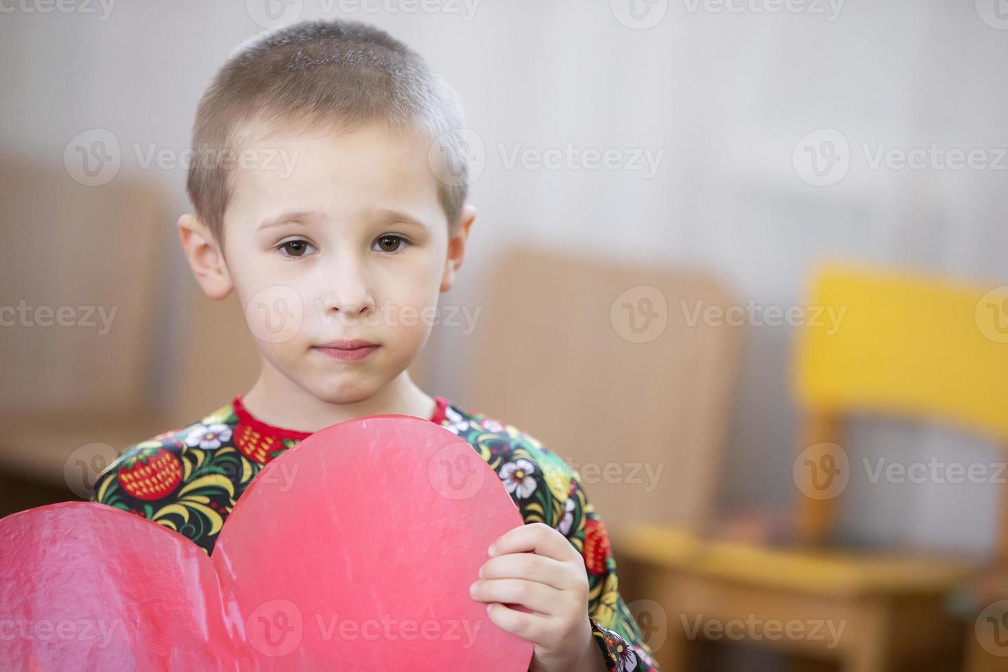 gracioso pequeño chico con un cartulina corazon.niño con enamorado. foto