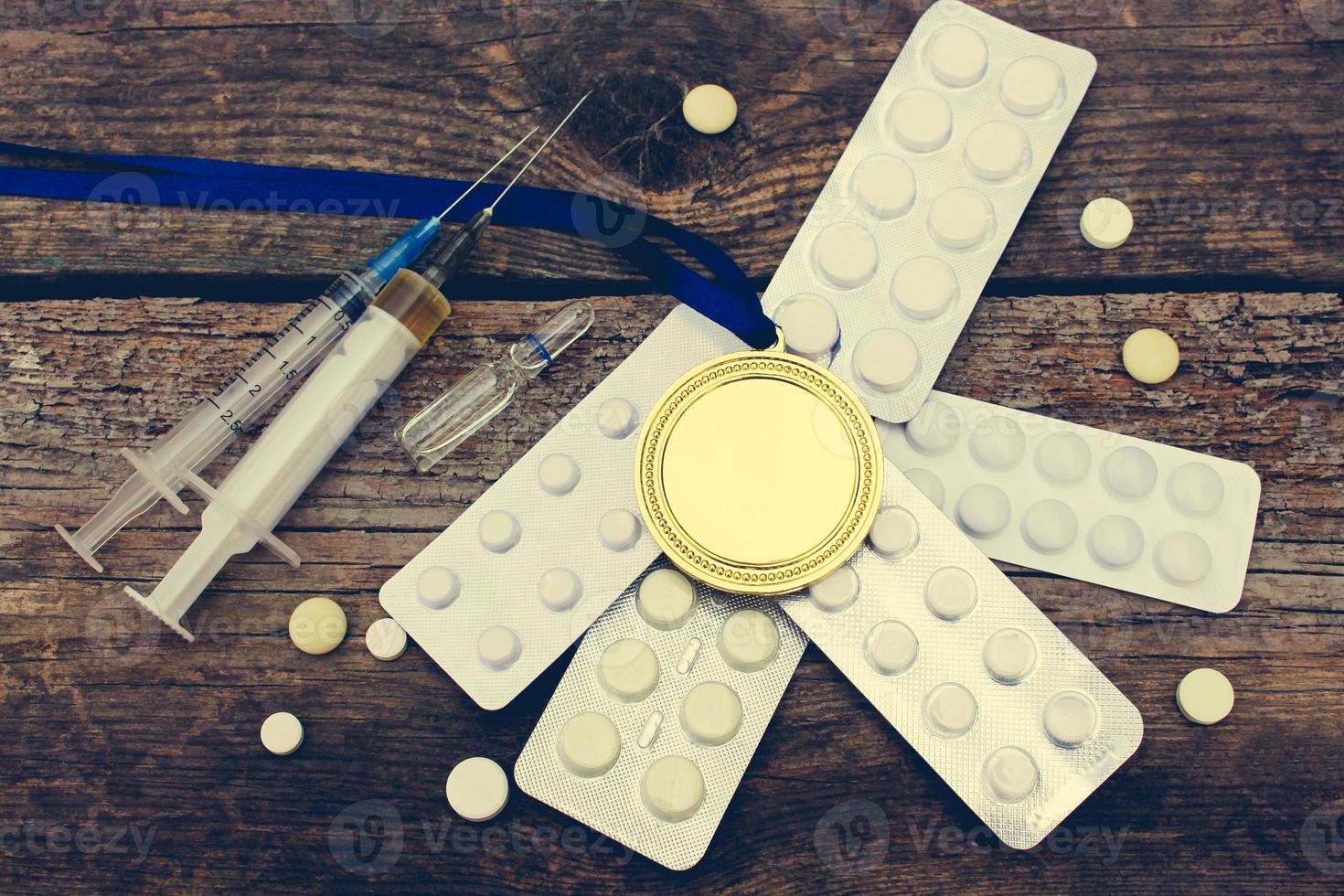 Sports medal and medicines on a wooden background. Toned image. photo