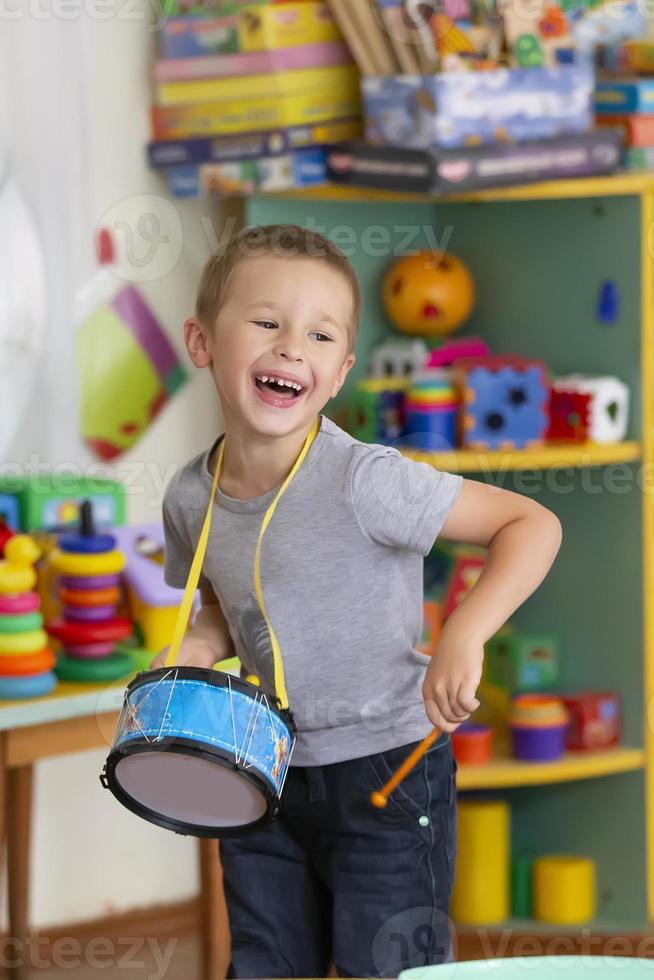 pequeño chico obras de teatro un juguete tambor. talentoso chico futuro músico foto