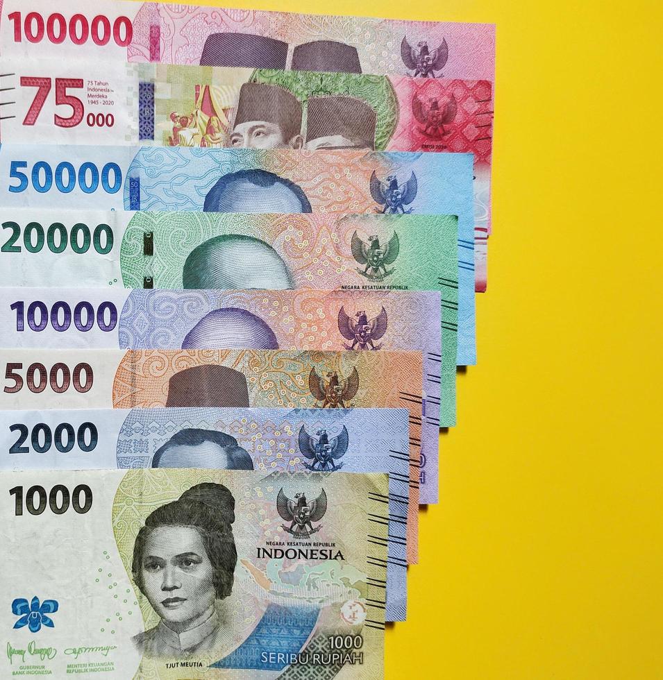 New banknotes issued in 2022 from Rp.1,000 to Rp.100,000. Indonesian rupiah currency concept isolated on a yellow background. Top view photo