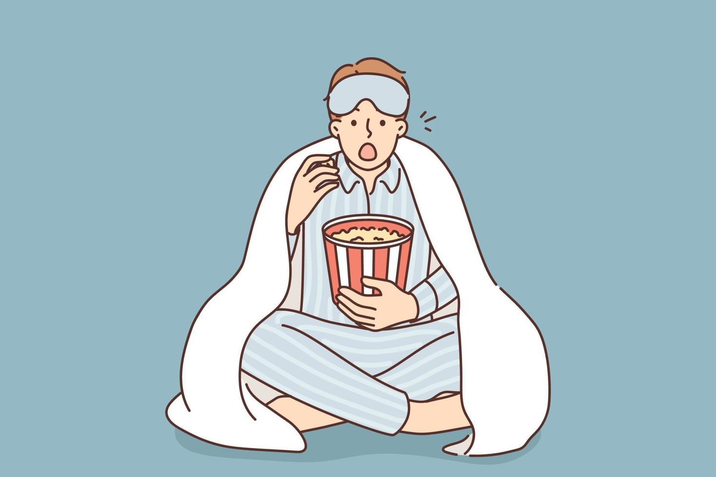 Man in pyjama under blanket eat popcorn watch movie at home. Surprised guy wear pajama enjoy movie night indoors with snacks. Vector illustration.
