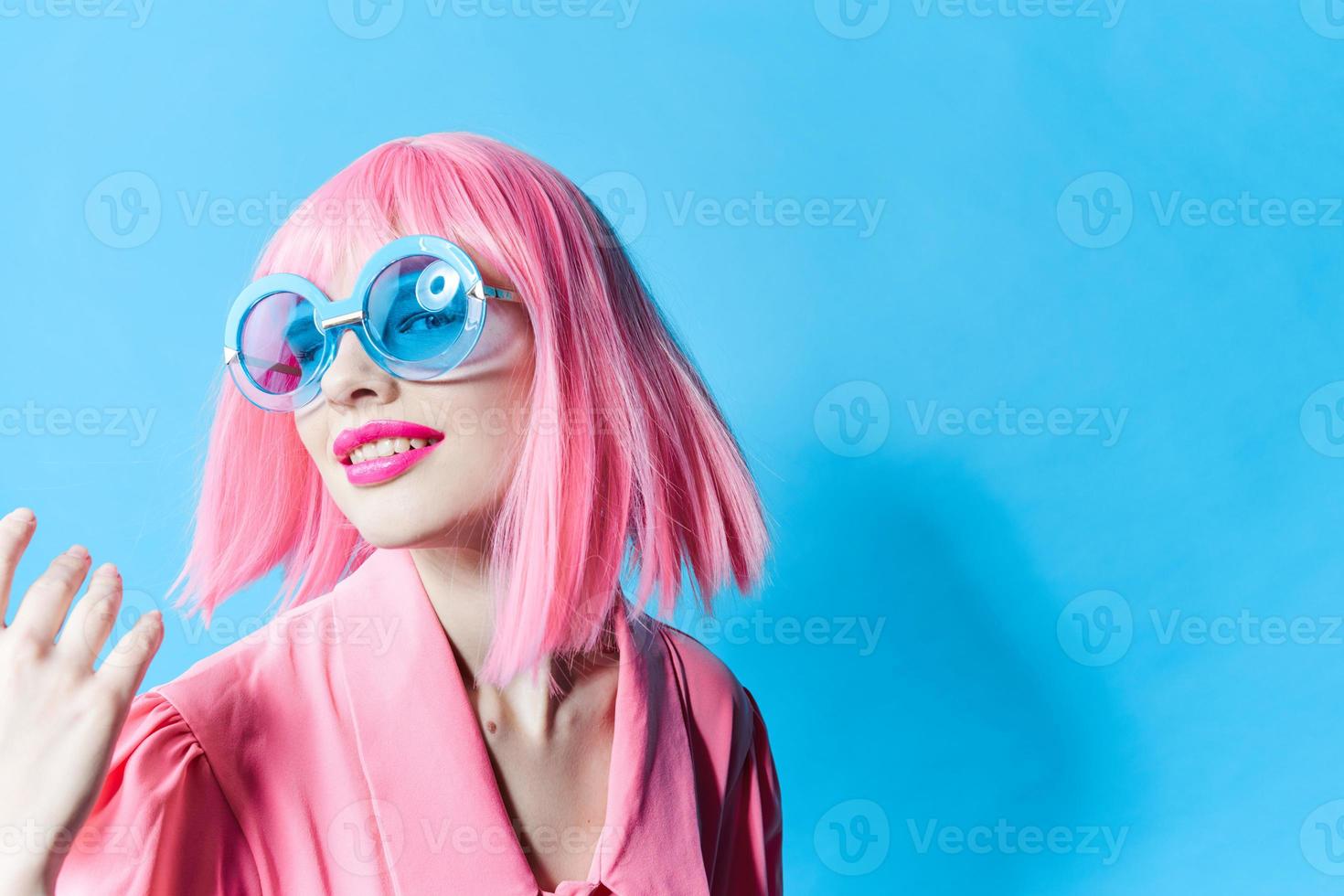 pretty woman in blue glasses wears a pink wig isolated background photo