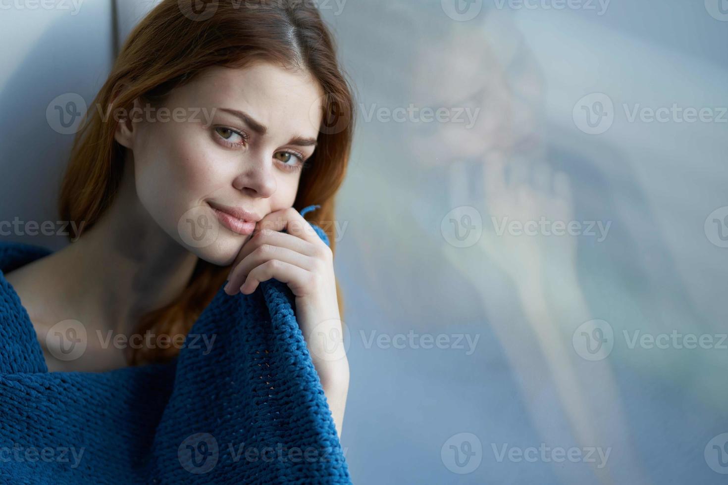 pretty woman sitting near the window with a blue plaid smile at home photo