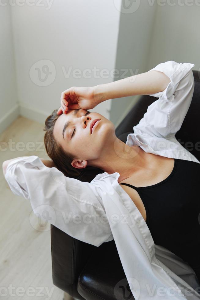 mujer acostado a hogar en el sofá retrato con un corto Corte de pelo en un blanco camisa, sonrisa, depresión en adolescentes, hogar fiesta foto