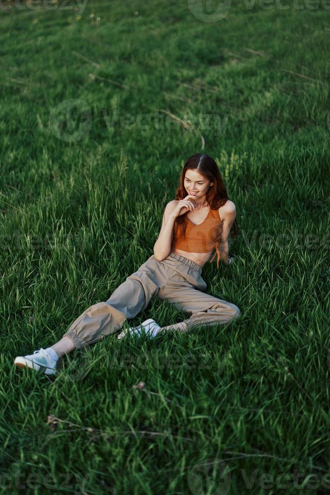 un mujer mentiras en Fresco primavera verde césped en un parque sin mosquitos o garrapatas y disfruta relajante mientras acecho el puesta de sol. el concepto de seguro al aire libre recreación foto