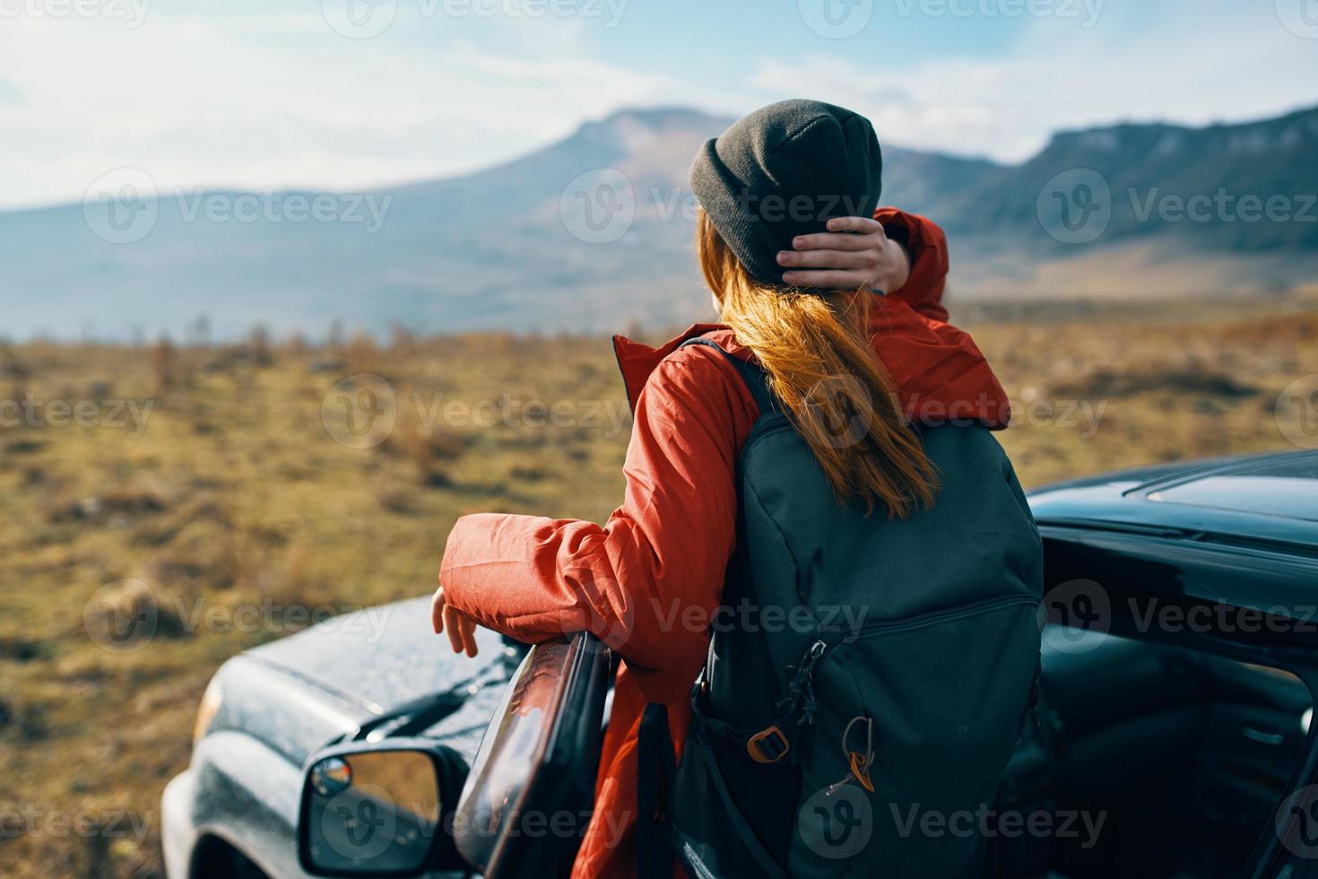 traveler in a hat with a backpack near the car door in nature photo
