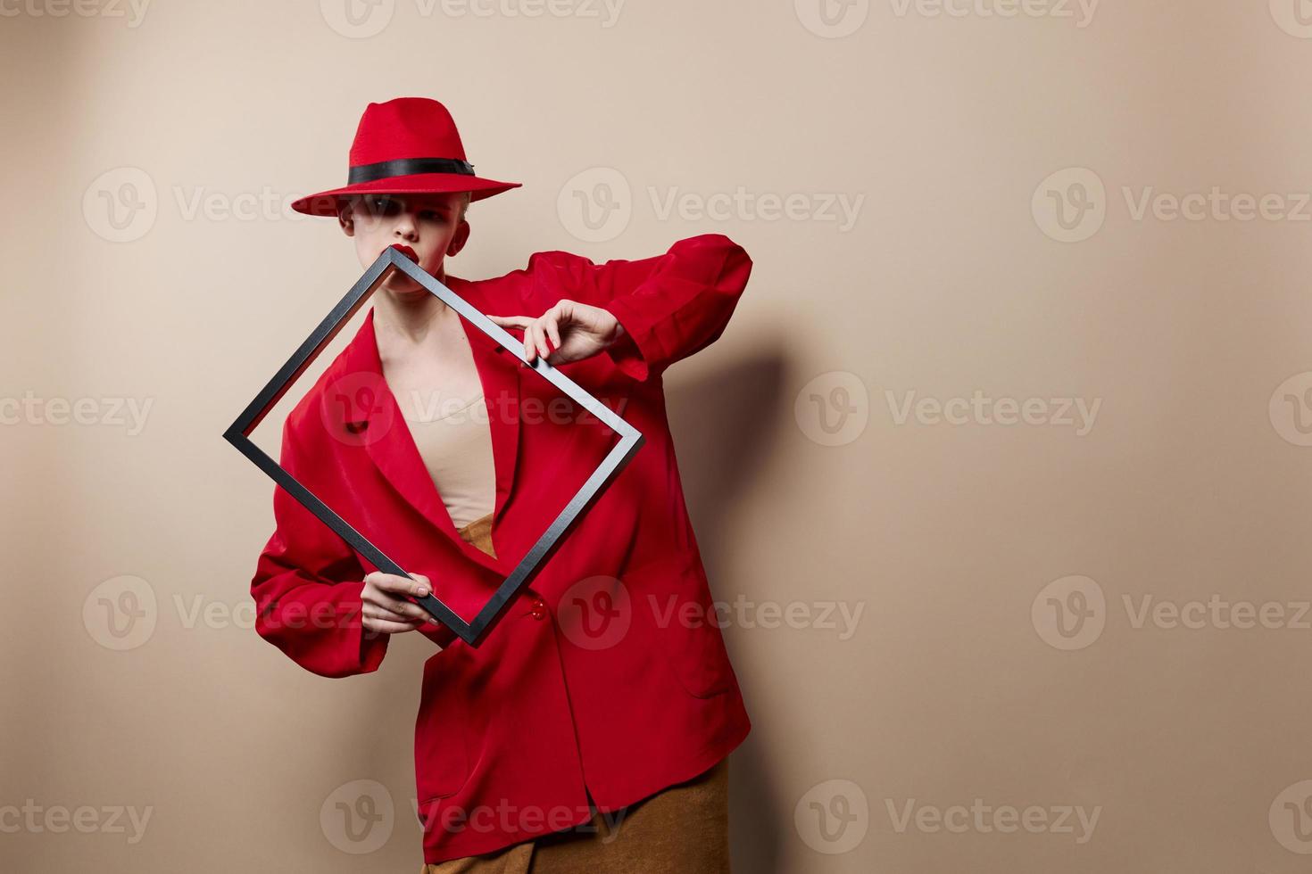 fashionable woman frame in hand in red hat and jacket beige background photo