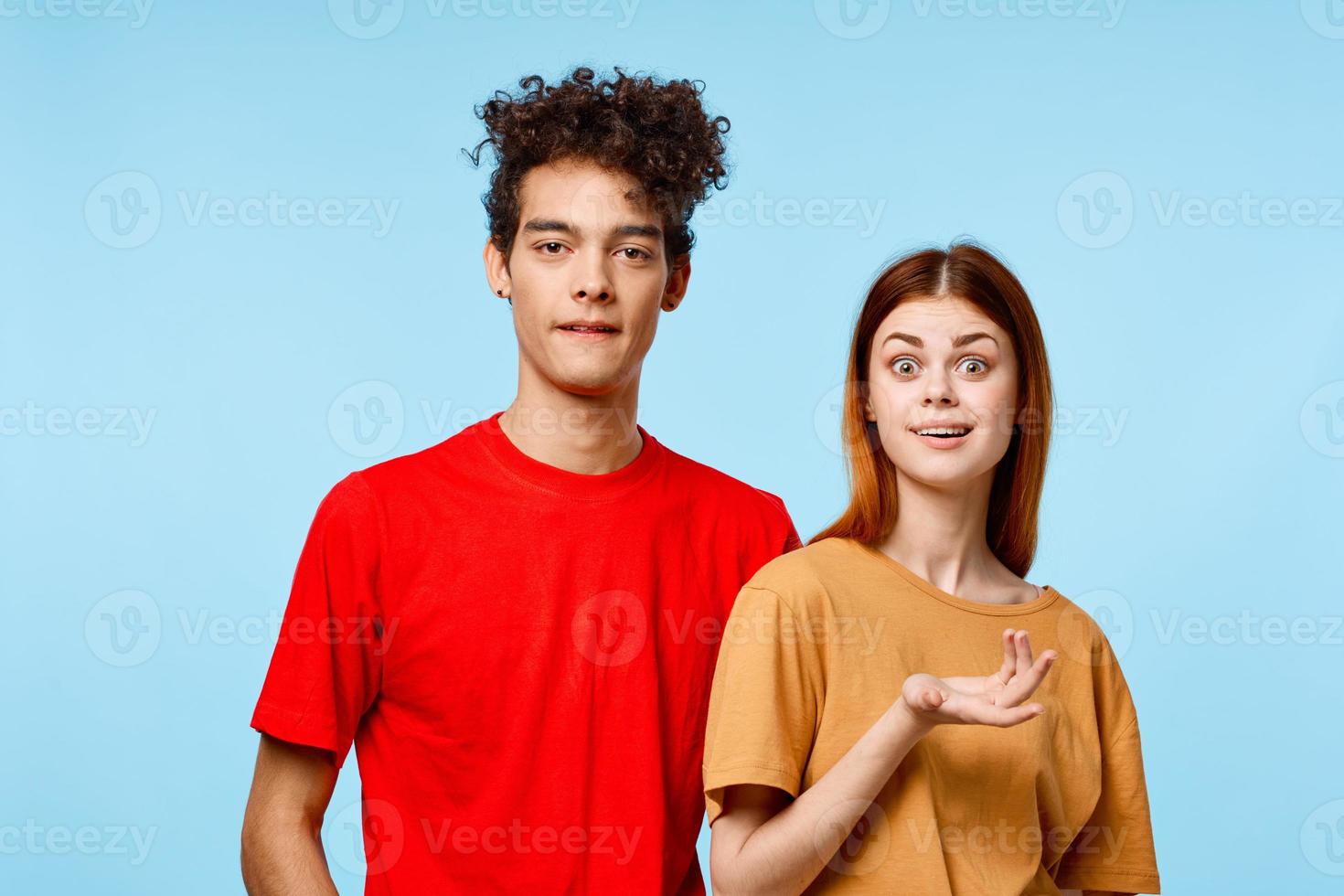 cheerful young couple in multicolored t-shirts communication studio blue background photo