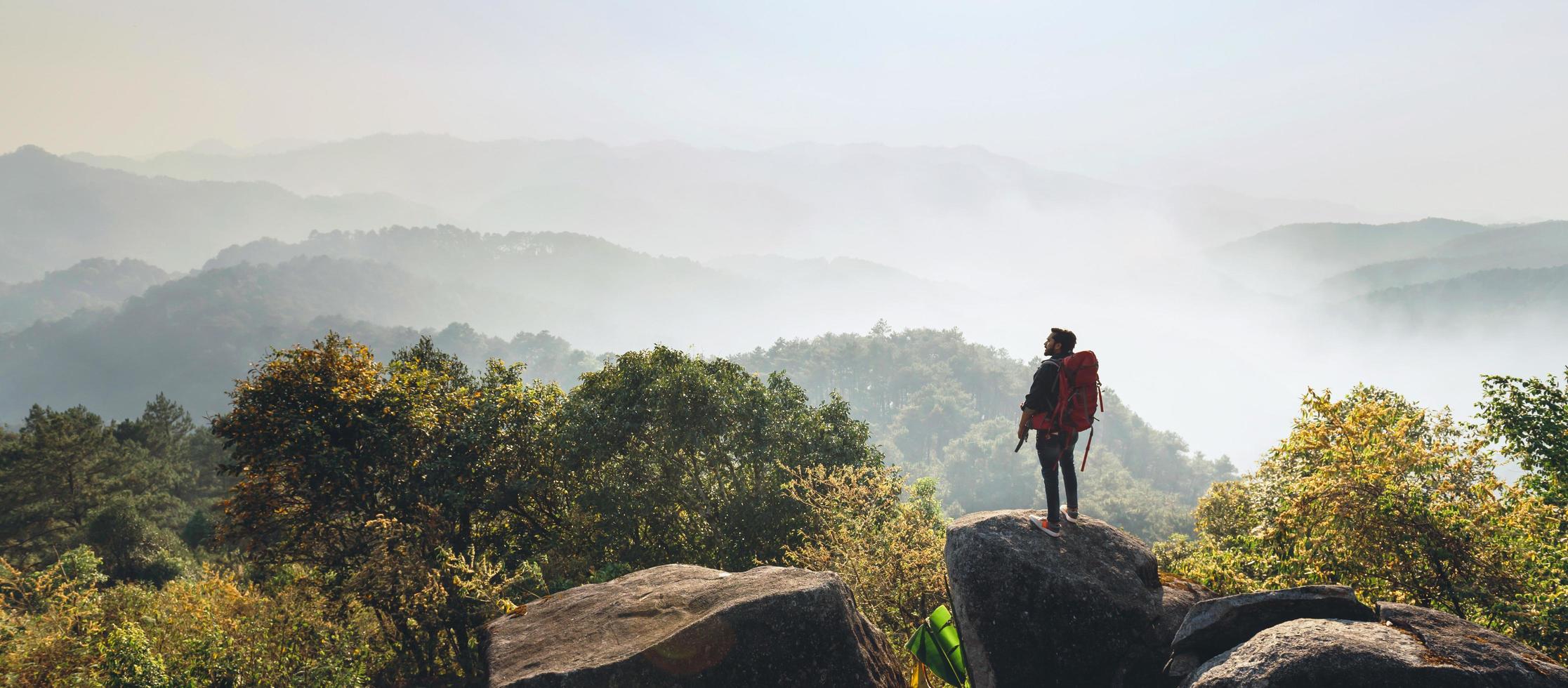 traveler standing at stone for look at view on top mountain photo