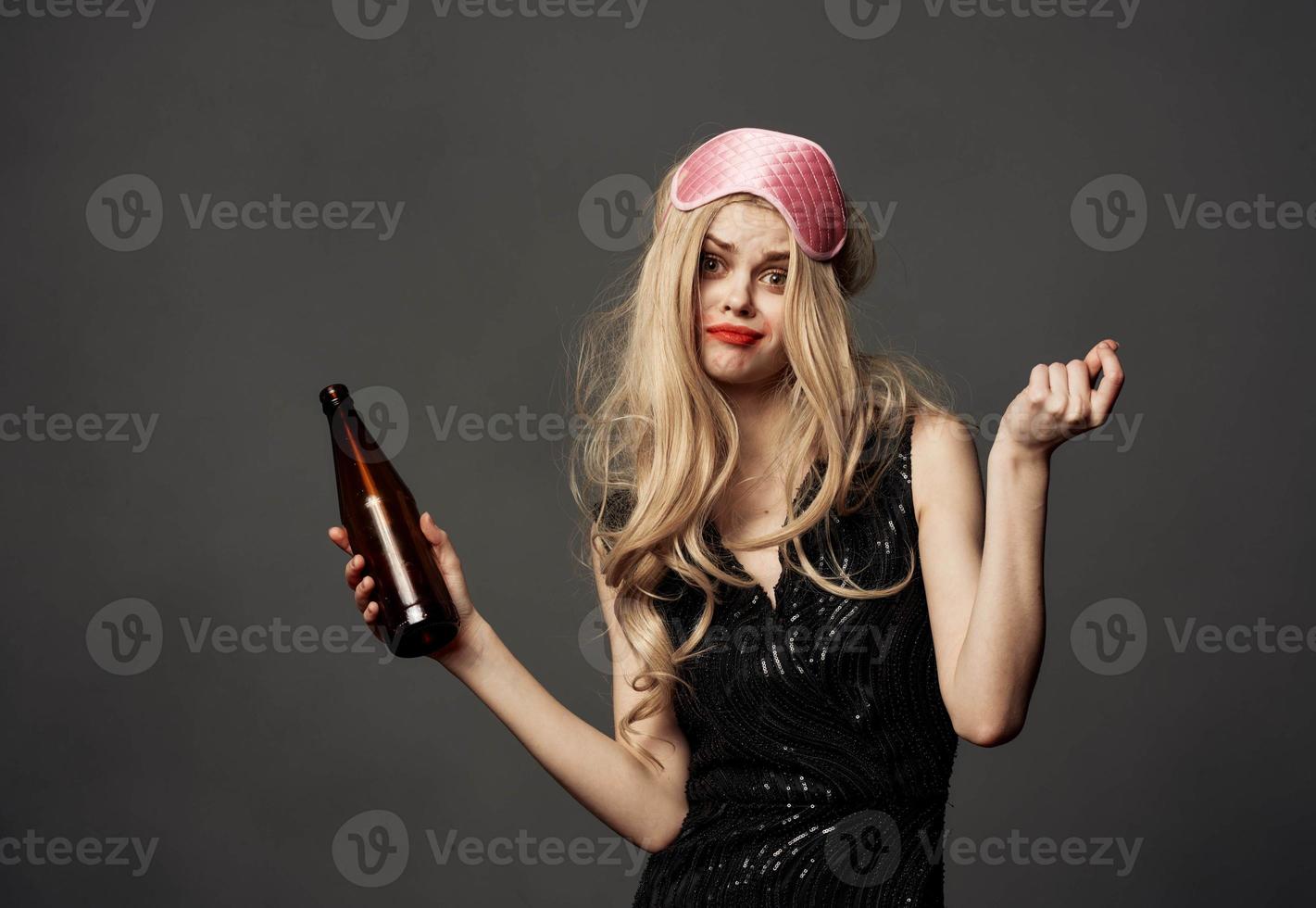 Beautiful blonde with a bottle of beer in her hand and a pink mask on her head photo