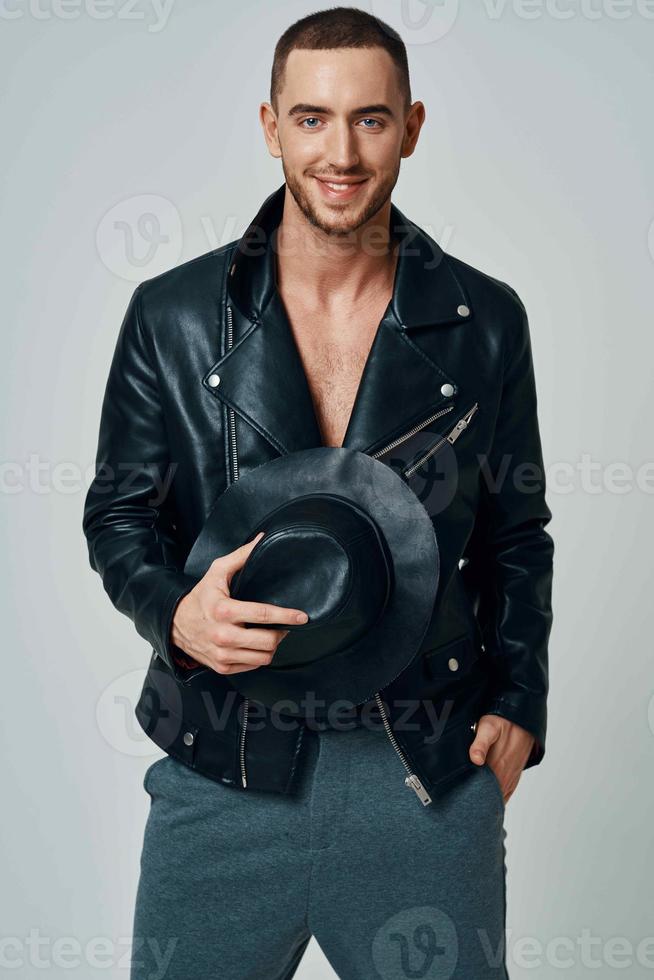 man in black leather jacket hat posing fashion confident light background photo