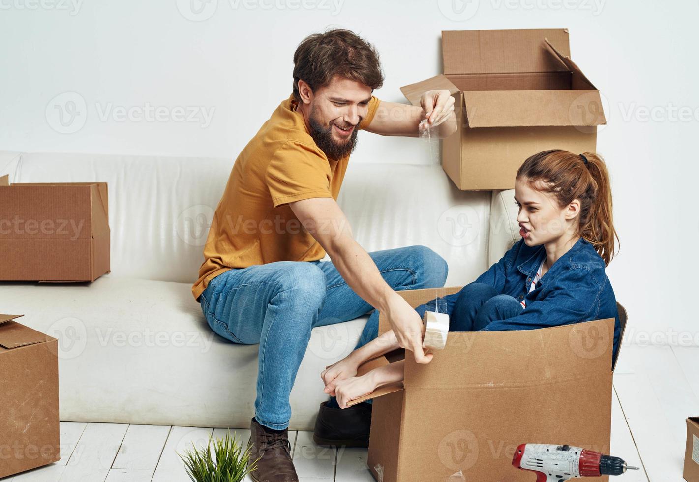 family young couple on the couch fun moving boxes with things photo