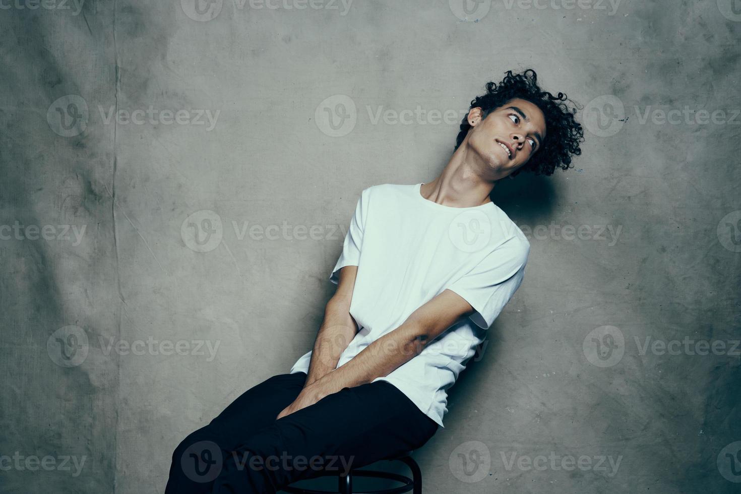 teenager with curly hair sits on a chair indoors on a fabric background emotions fun photo