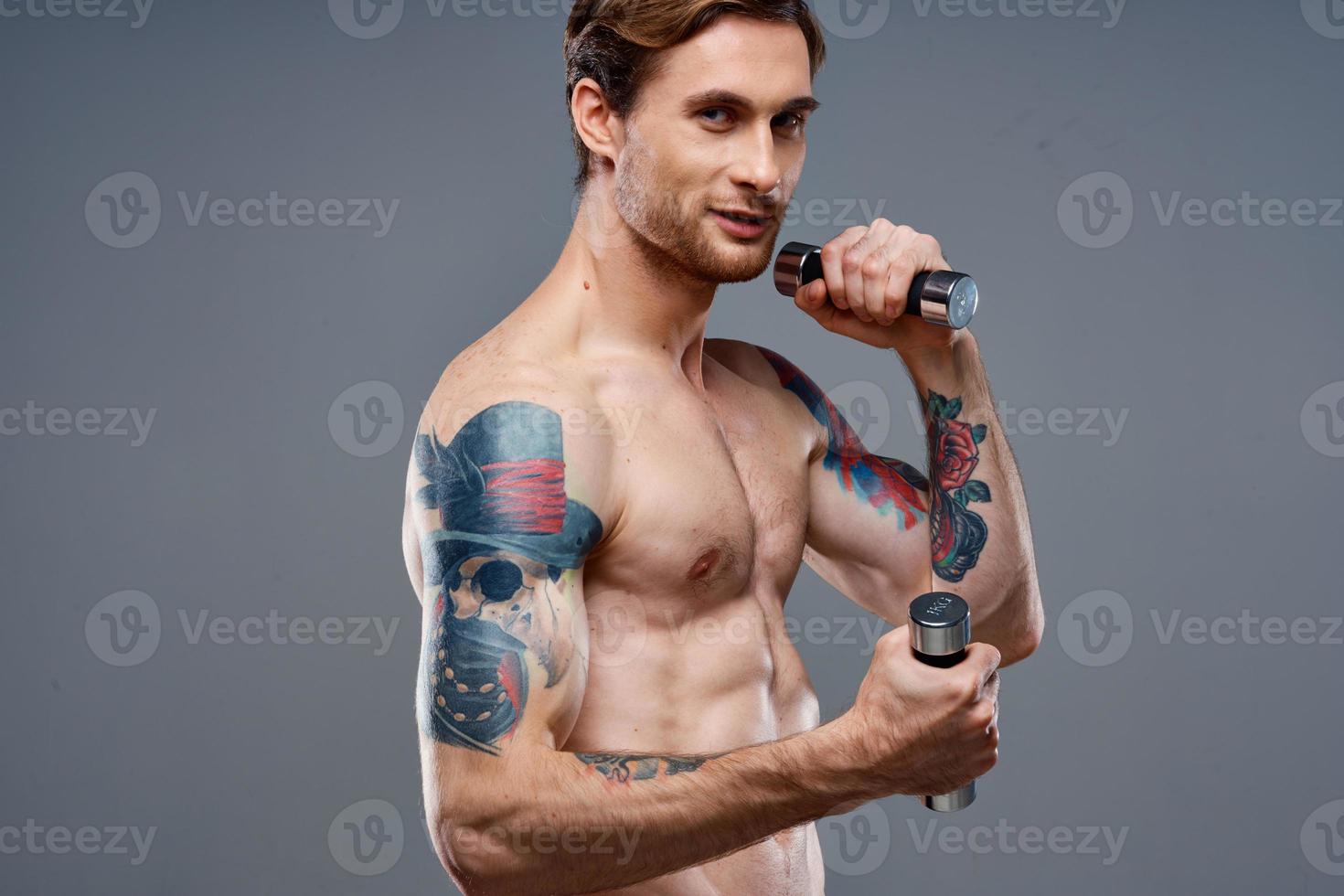 masculino atleta con un tatuaje en su brazo desnudo torso inflado músculos pesas aptitud foto