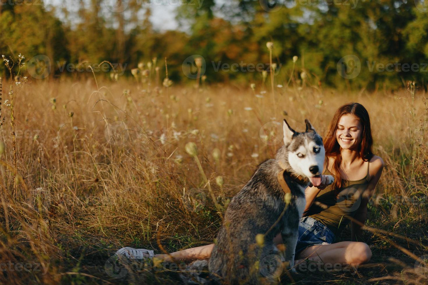 Woman sitting in field with dachshund dog smiling while spending time outdoors with dog friend photo