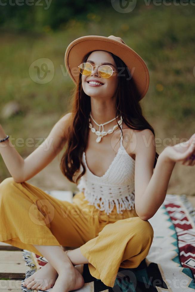 A hippie woman meditating in nature in the lotus position in the sunset light photo