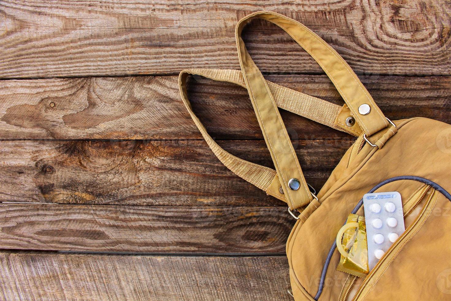 The birth control pill and condom falls out of pocket with handbags on wooden background. Toned image. photo