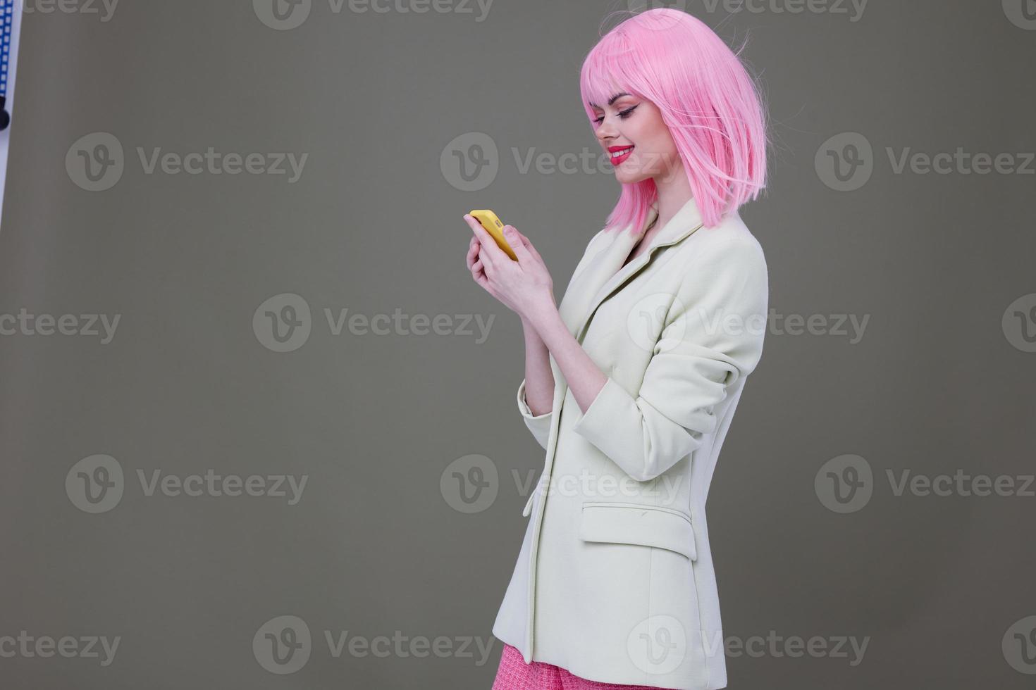 bonito mujer en blanco chaqueta de sport rosado peluca con teléfono foto