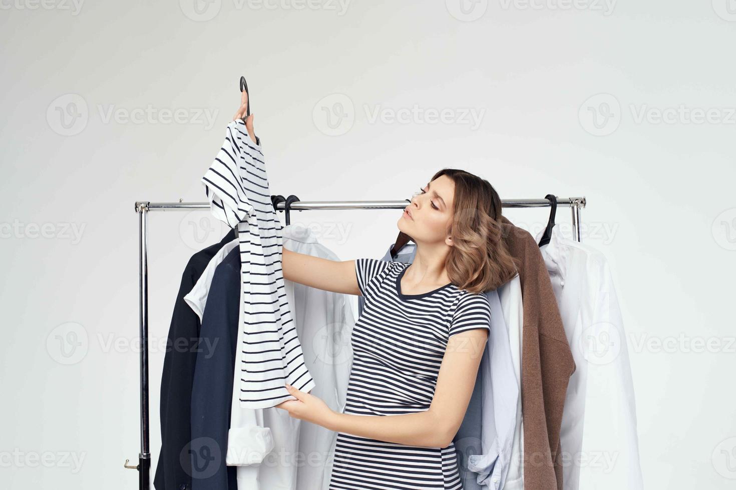 pretty woman next to clothes fashion fun light background photo