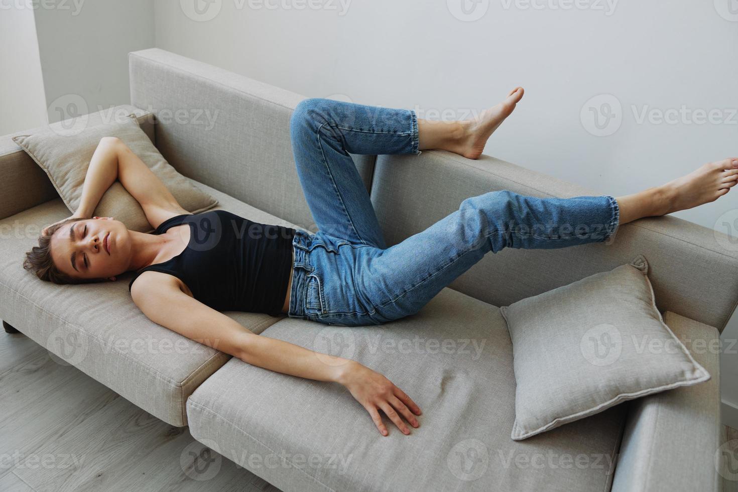 joven mujer con corto Corte de pelo pelo teniendo divertido a hogar en el sofá sonrisa y felicidad, vacaciones a hogar, natural posando sin filtros, gratis Copiar espacio foto