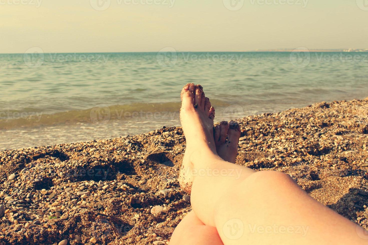 Female feet on the blue sea background. A woman sunbathes on the beach. Girl taken pictures of her feet self. Toned image. photo