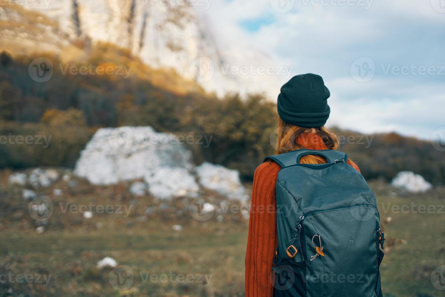 woman tourist in a hat with a backpack climbs the mountains in nature back view photo