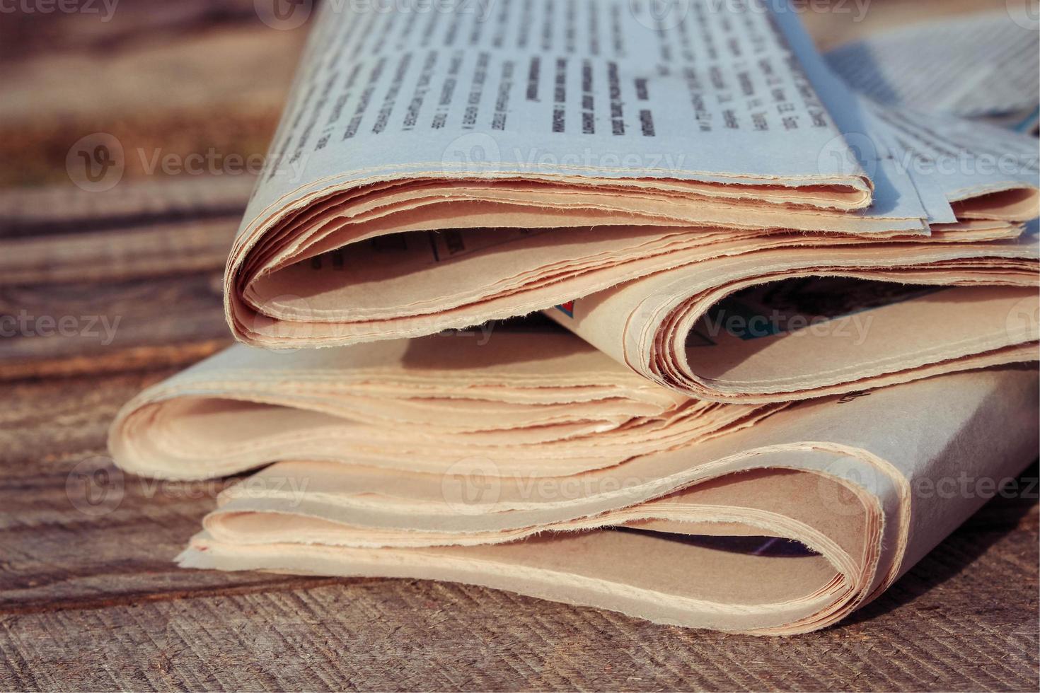 Newspapers on old wood background. Toned image. photo