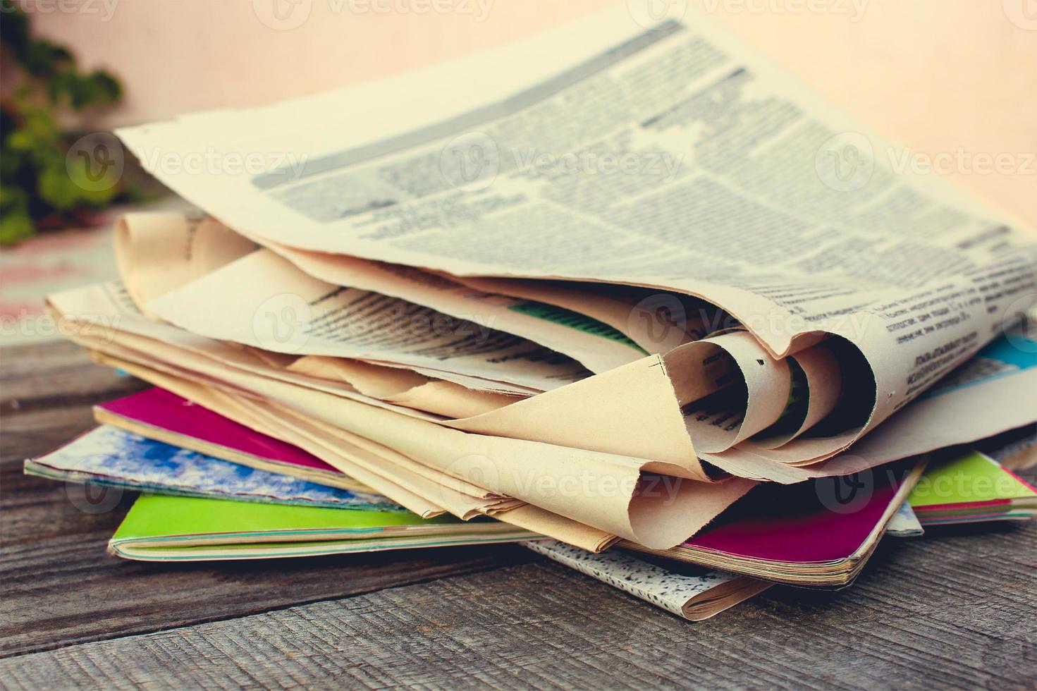 Newspapers and magazines on old wood background. Toned image. photo