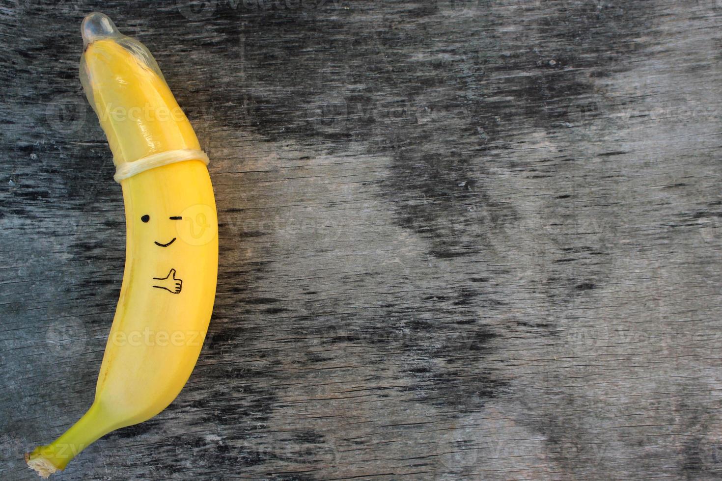 Banana with condom on the old wooden background. photo