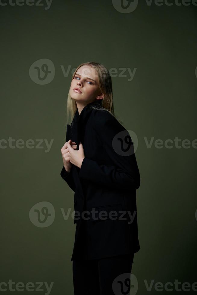 A concept for marketplaces and clothing brands. Full-length portrait of a blonde holding a jacket collar posing on a green background in the studio photo