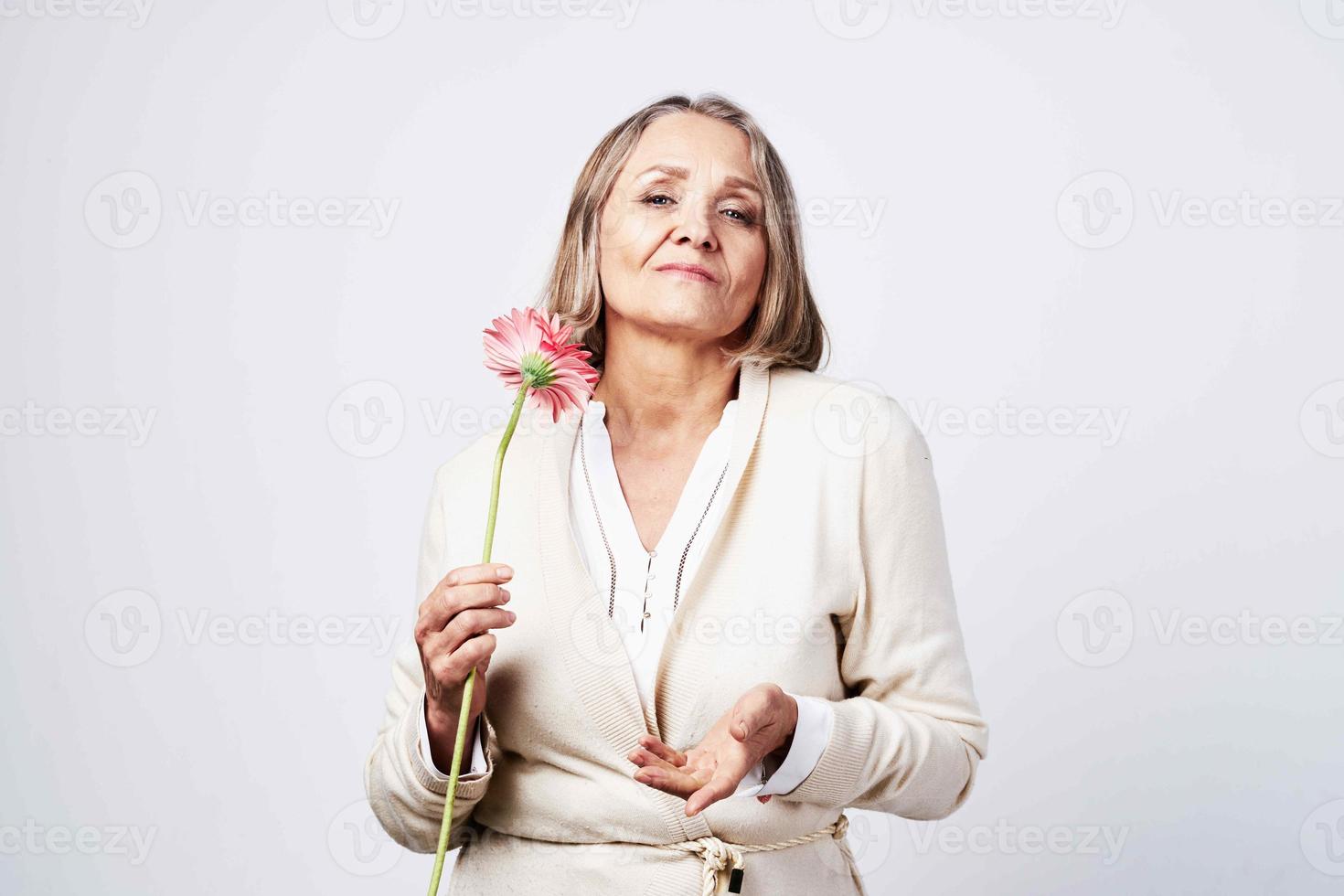 elderly woman in a robe holding a flower gift light background photo