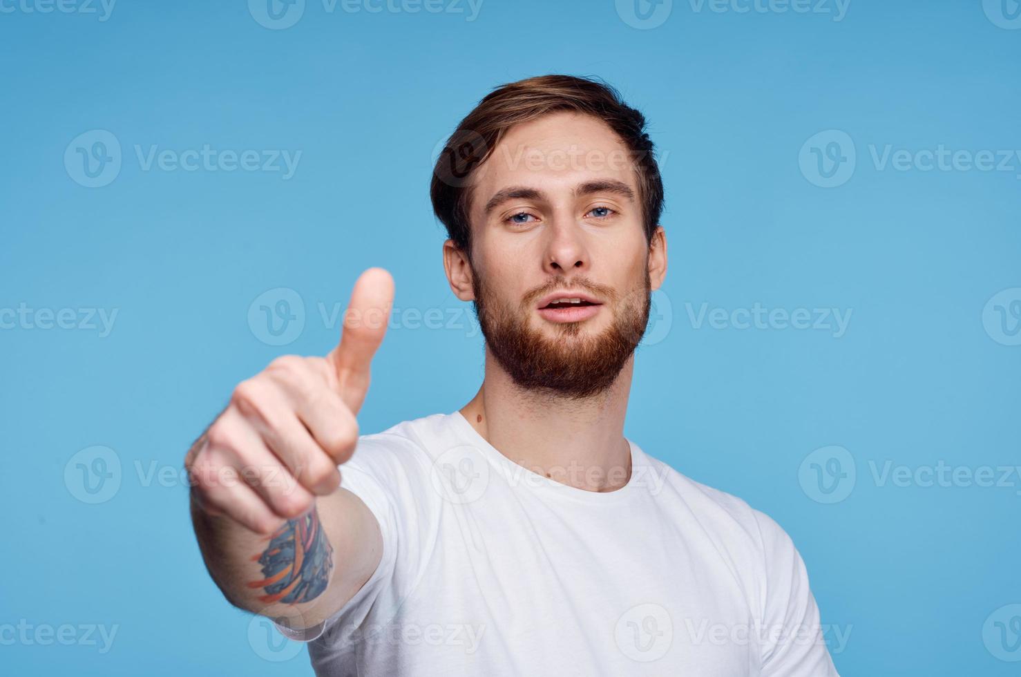 man in white t-shirt showing thumb up blue background studio photo