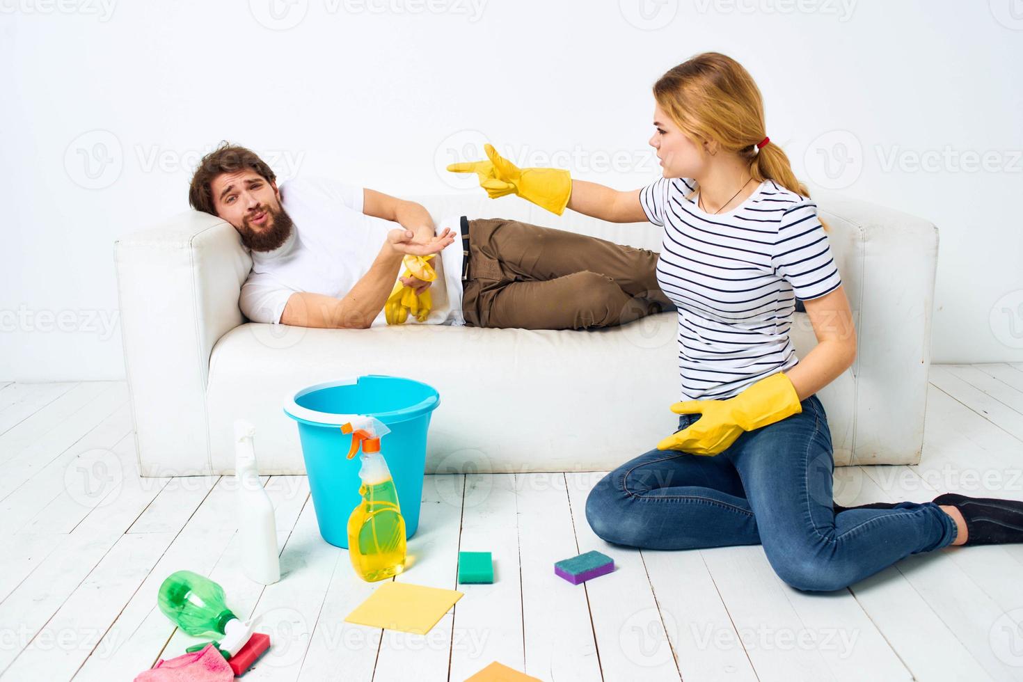 The wife cleans up while the husband lies on the couch interior housework photo