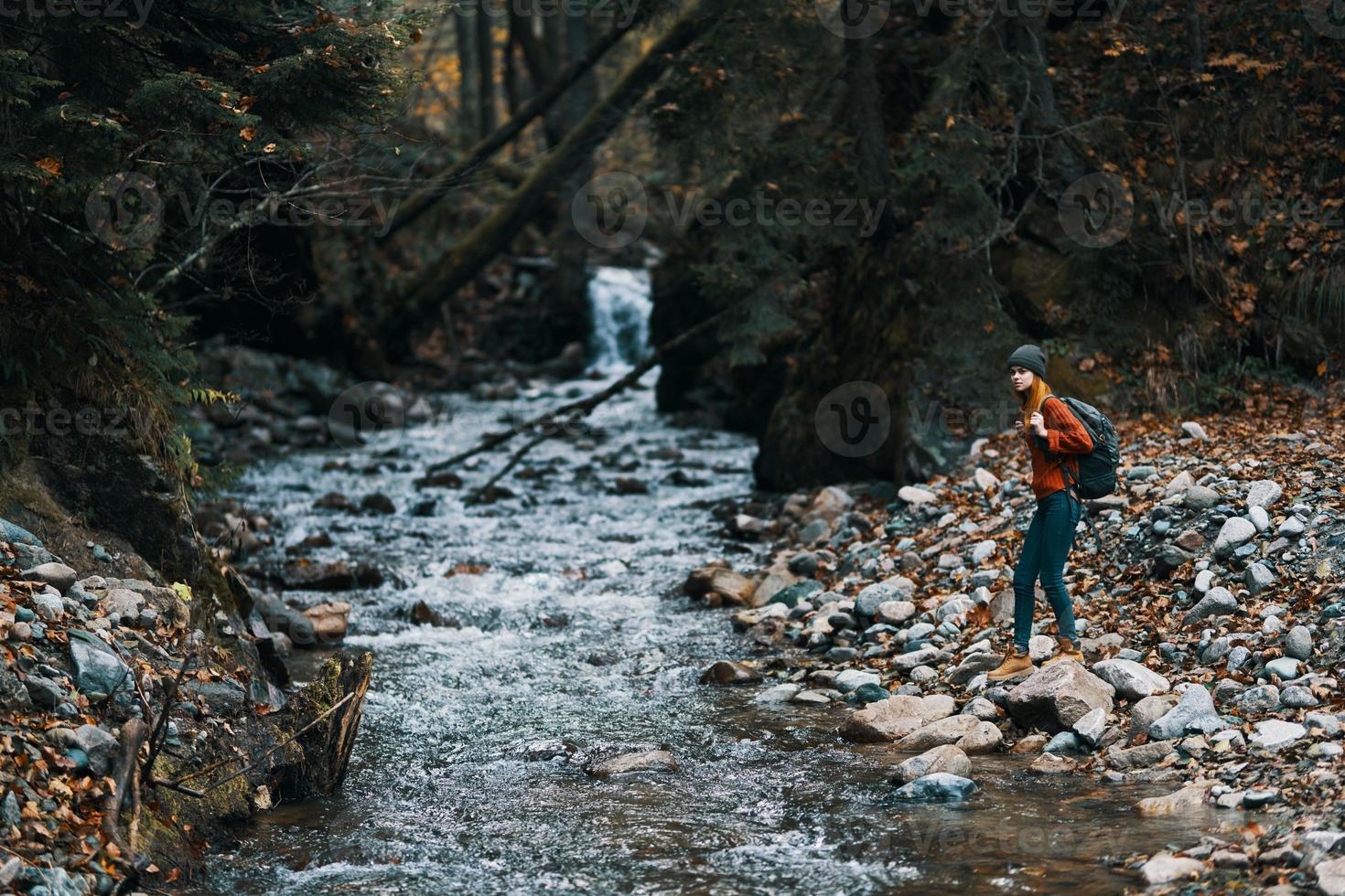 woman tourist in warm clothes with a backpack on the river bank and tall trees landscape photo