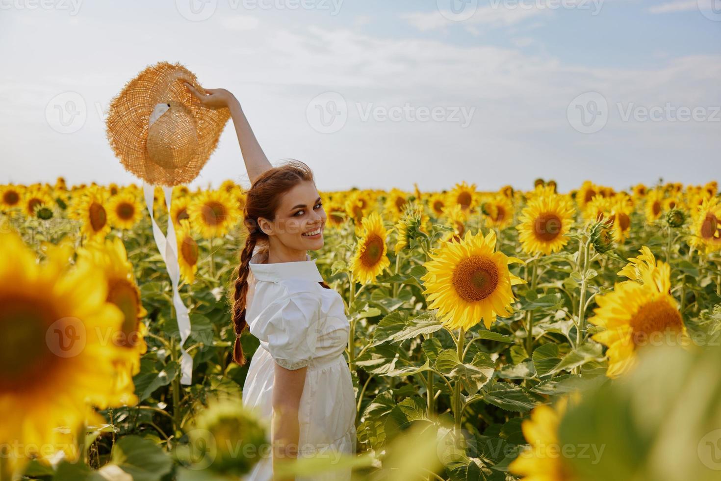 mujer con elevado arriba manos en un campo de girasoles Paja sombrero paisaje naturaleza foto