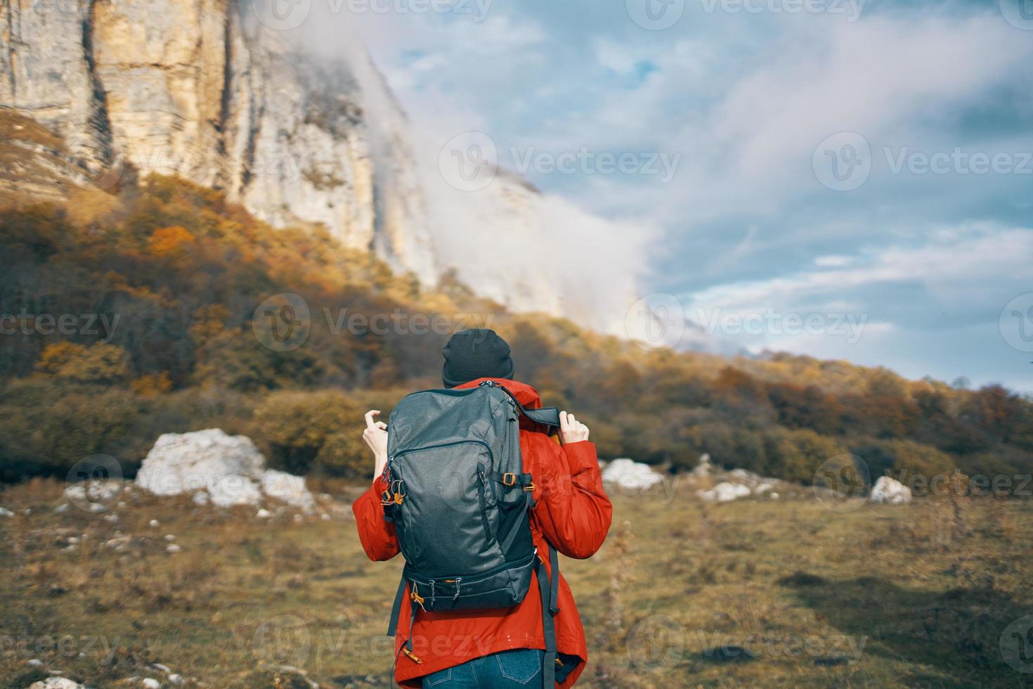 traveler with backpack in autumn in the mountains blue sky clouds high rocks landscape photo