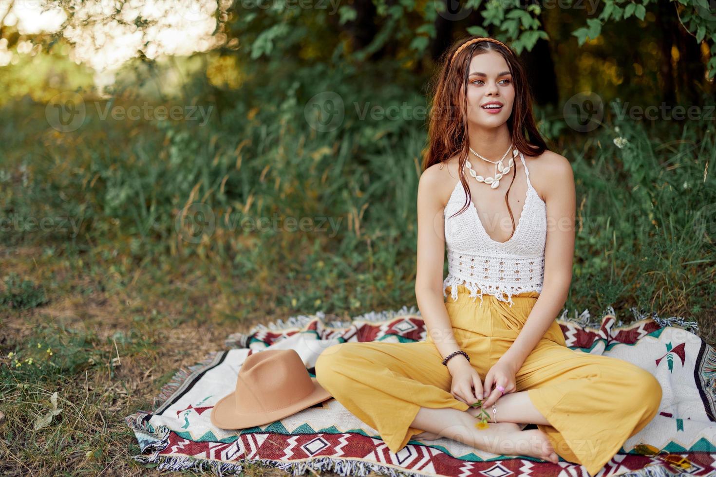 Girl dressed as a hippie eco relaxing in the park, sitting on a blanket in the sunset, relaxed lifestyle photo