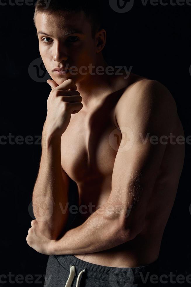 sporty guy with pumped up arm muscles on black background portrait cropped view photo