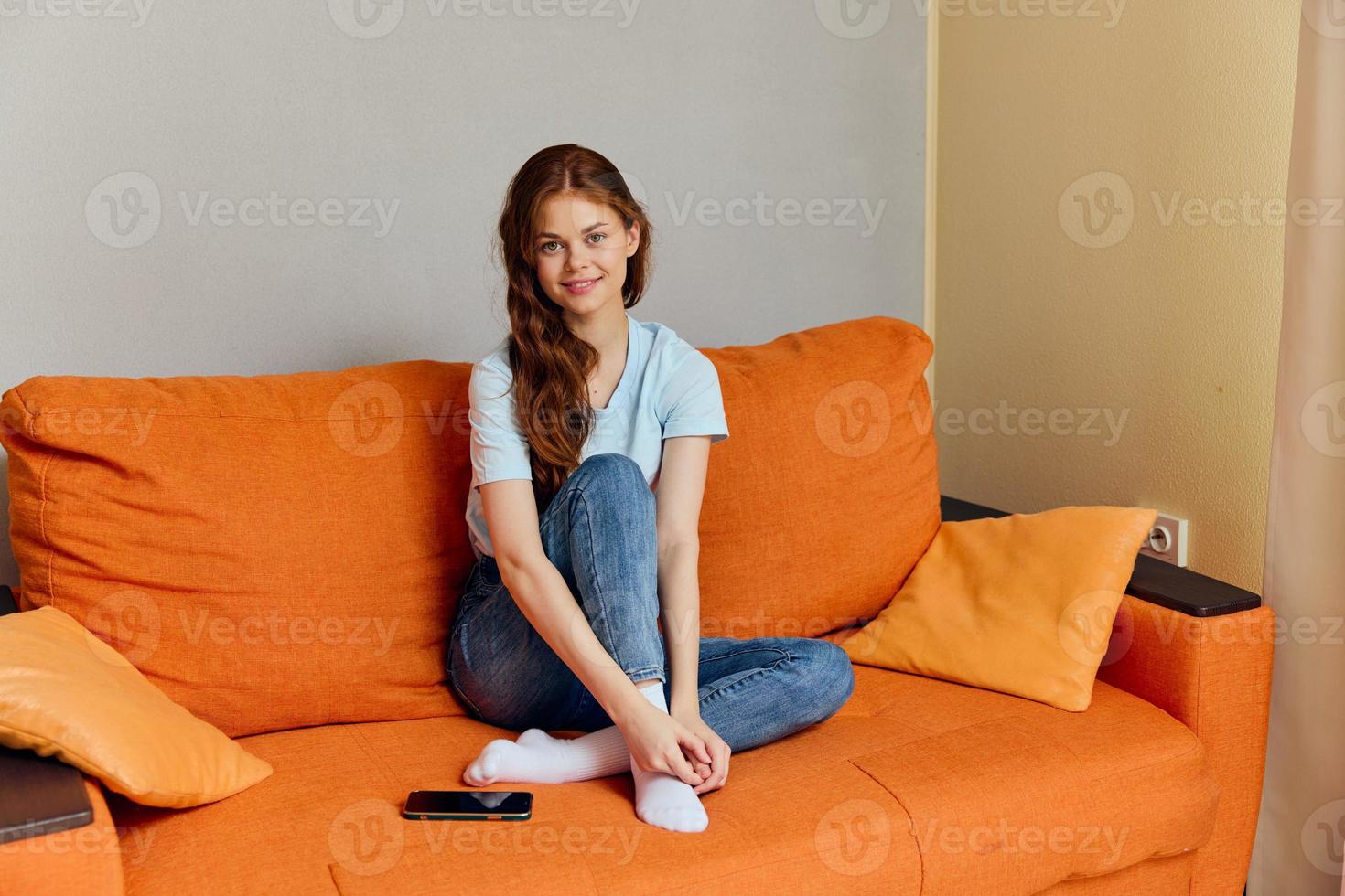woman chatting on the orange couch with a smartphone Lifestyle photo