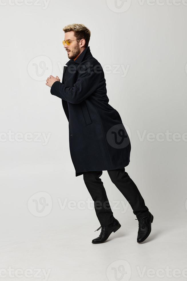 Cheerful man fashionable glasses coat studio motion emotions photo