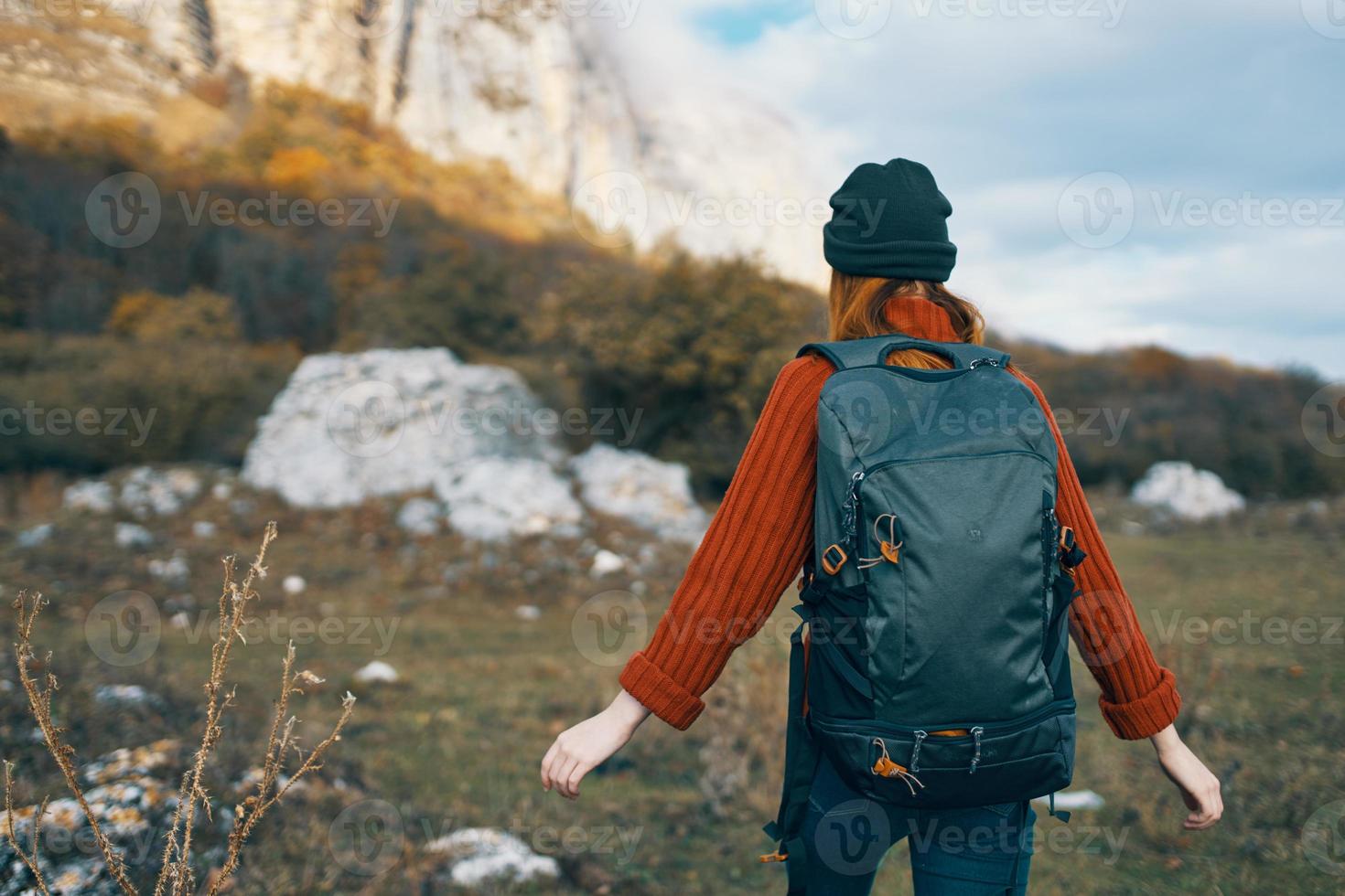 woman tourist in a hat with a backpack climbs the mountains in nature back view photo