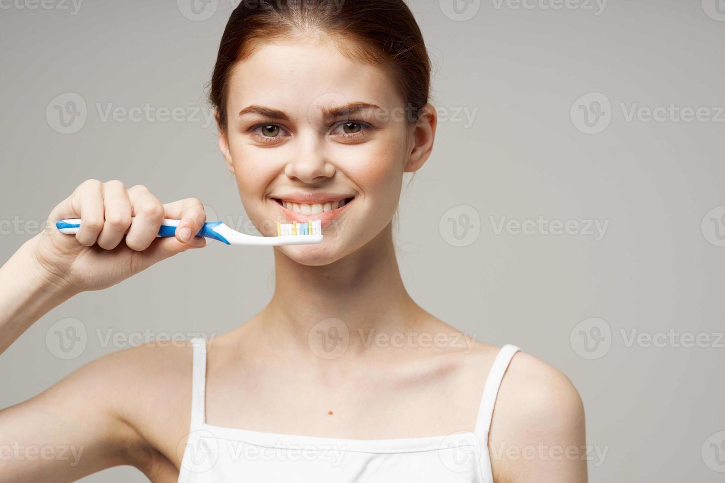 pretty woman toothpaste brushing teeth dental health light background photo