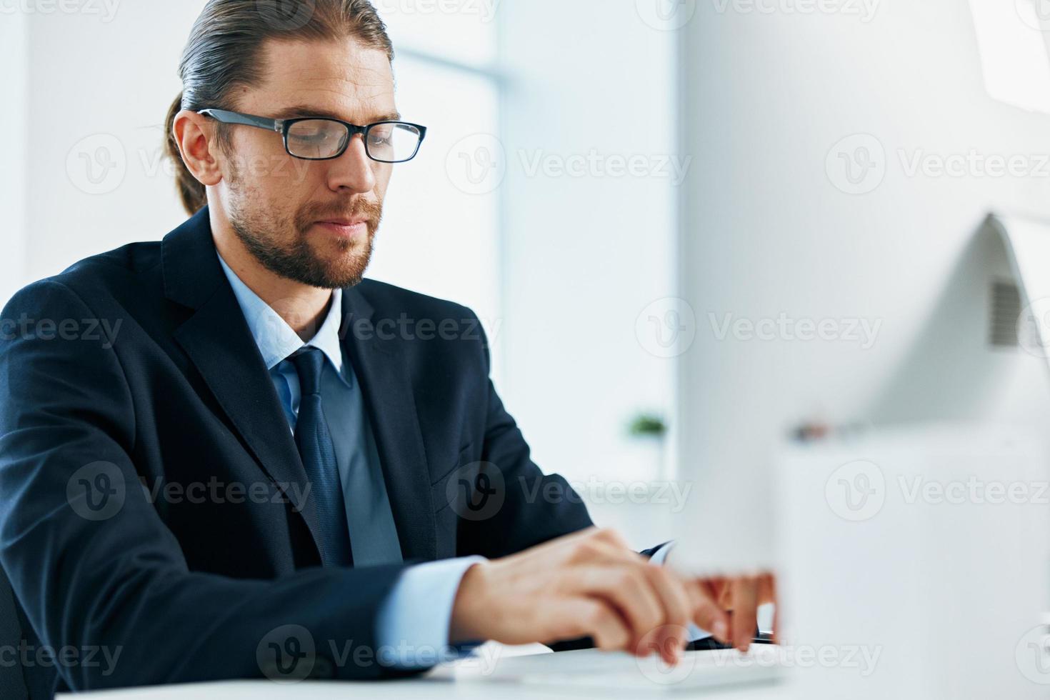 business man in a suit sitting at his desk tired in front of a computer photo