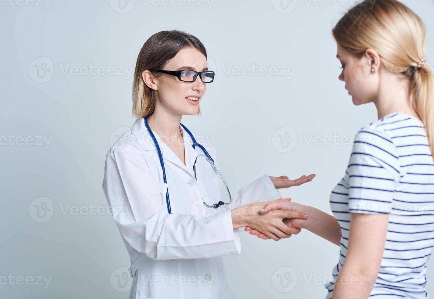 Woman doctor and patient shaking hands on a light background communicating medicine photo