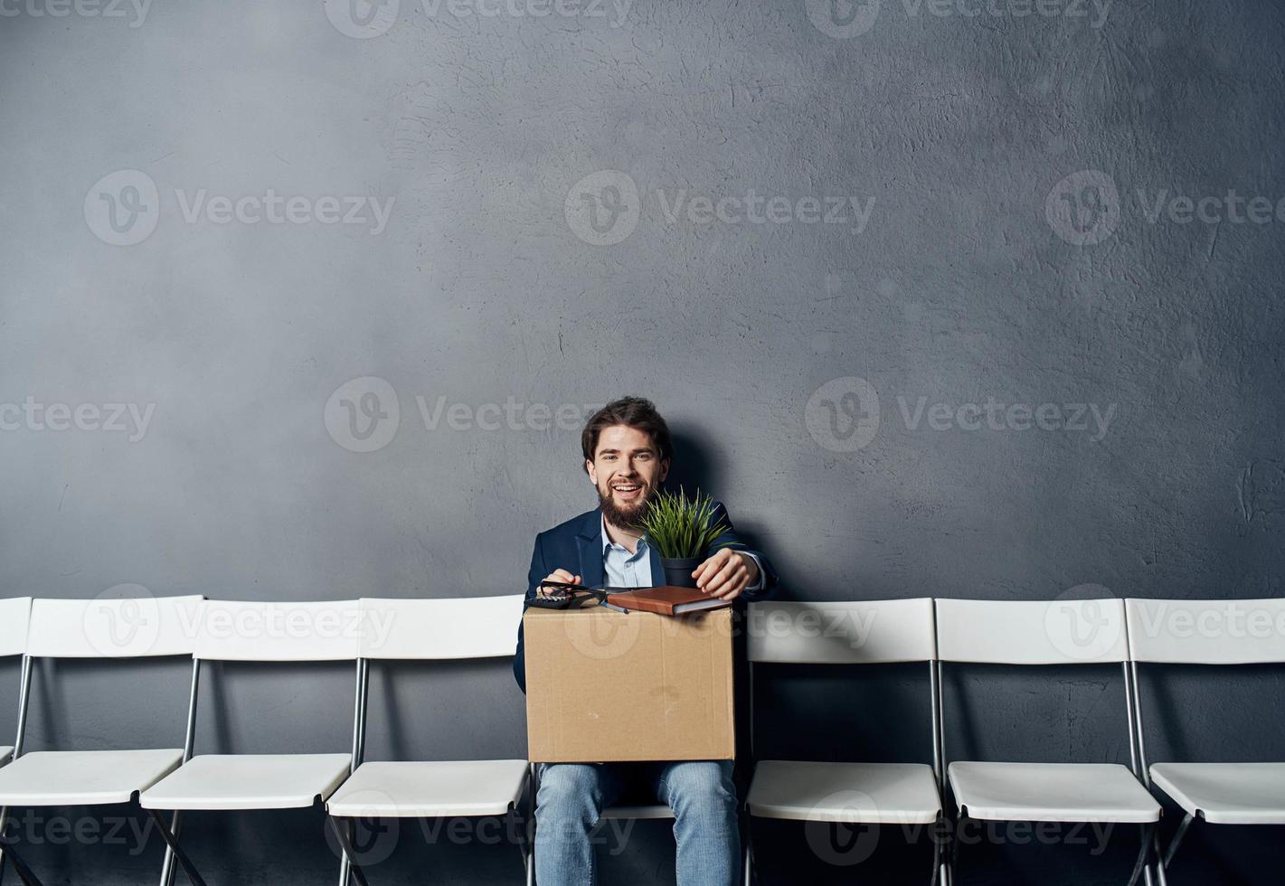 un hombre con un caja se sienta en un silla con cosas documentos despido foto