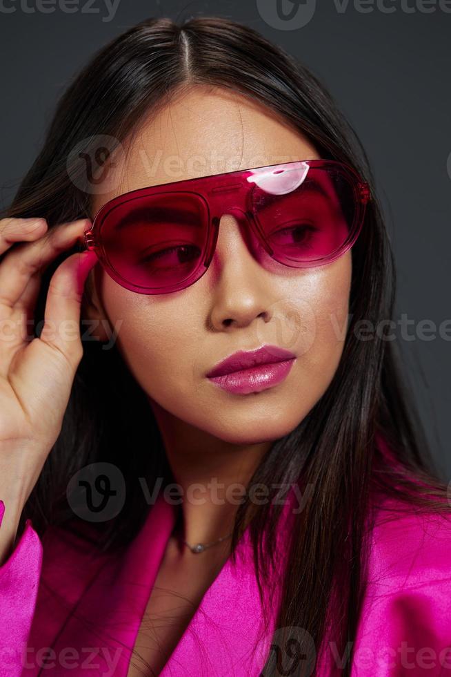 Brunette posing pink mini dress charm sunglasses Gray background photo