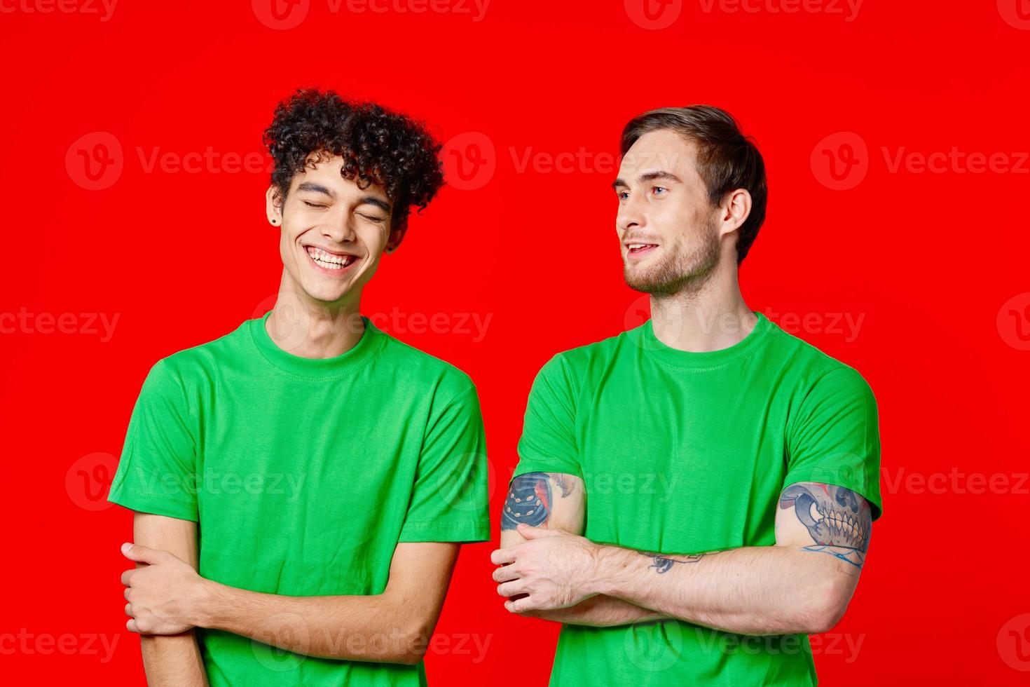 two men in green t-shirts are standing side by side communication photo