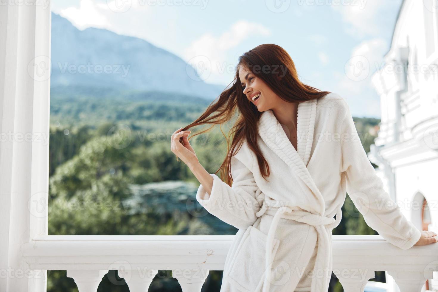 Portrait of young woman white robe admire the view from the window Perfect sunny morning photo