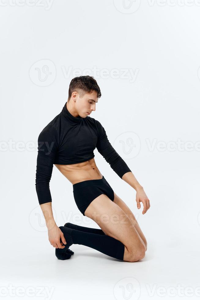 sexy man in black panties in Switzerland and in socks kneels light background in full growth photo