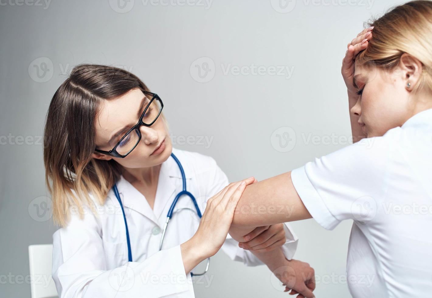 Doctor sits on a chair and woman patient indoors on a light background cropped view photo